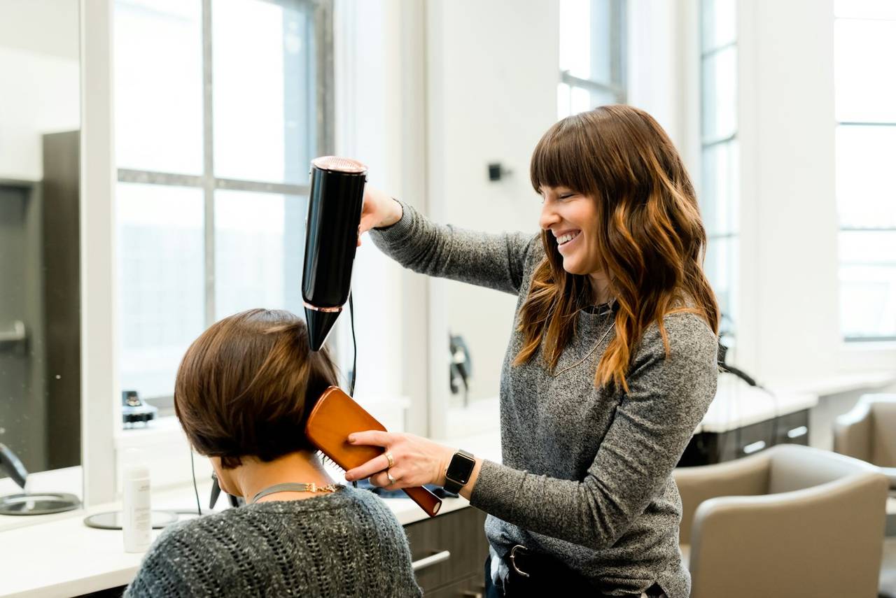 A stylist blow-drying a client’s hair