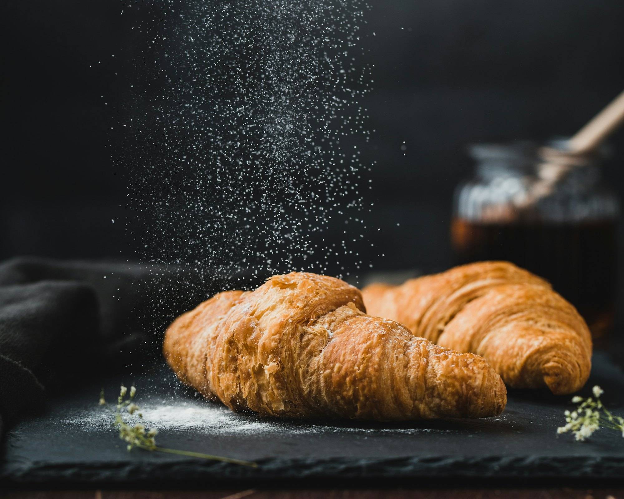 Croissants dusted with sugar on a dark board