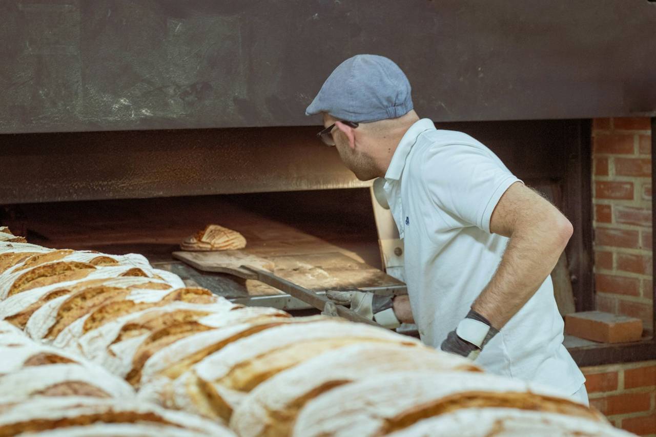 The baker loading loaves into the oven